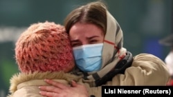 A woman fleeing Ukraine reacts as she receives a hug from a volunteer after arriving at Berlin's central station in March. 