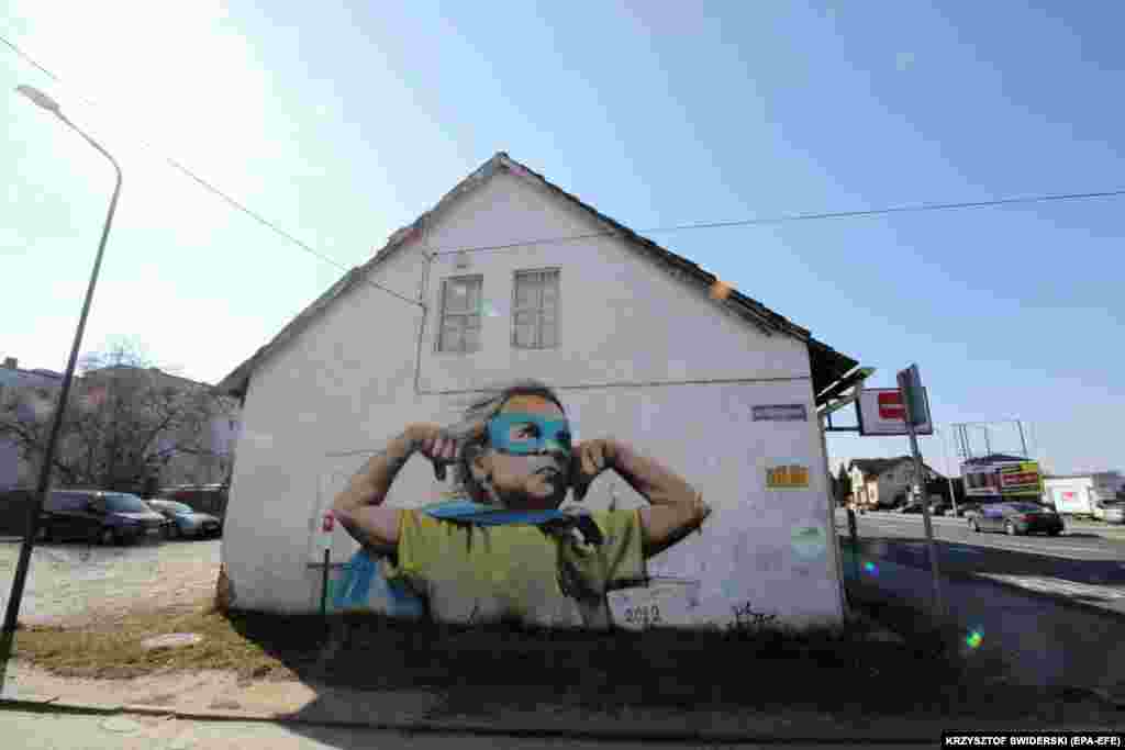 A mural showing a little Ukrainian girl as a &quot;super girl&quot; by an anonymous artist adorns the side of a house in Kedzierzyn-Kozle in southern Poland.