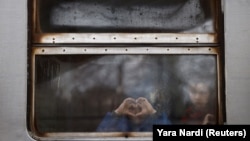  Деца гледат през прозореца на украински трен малко преди да отпътуват от гарата в Лвов, с цел да се изтеглят към прилежаща Полша. 