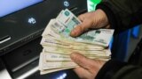 This image shows a person holding cash withdrawn from an ATM machine at a Sberbank branch.