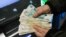 This image shows a person holding cash withdrawn from an ATM machine at a Sberbank branch.