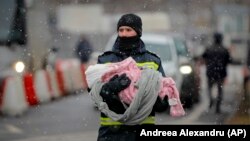 Román tűzoltó visz egy menekült csecsemőt a román–ukrán határnál, Siretnél március 7-én