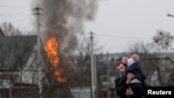 Helyi férfi a gyermekével a heves tüzérségi támadás alatt álló, Kijevhez közeli Irpinben 2022. március 6-án