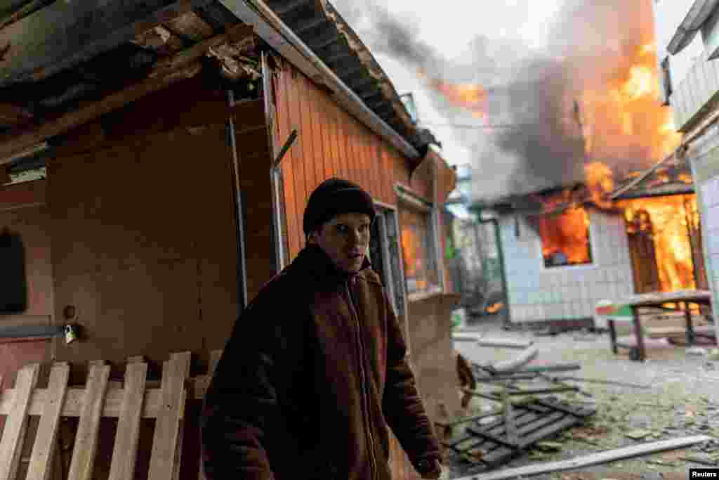 Një banor duke lëvizur pranë një shtëpie të përfshirë nga flakët, pas bombardimeve të fuqishme nga forcat ruse në Irpin, më 6 mars.