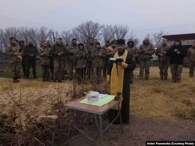 آنتون پاناسنکو، کشیش ارتدوکس در حال اجرای مراسم مذهبی پیشاپیش دسته‌ای از سربازان اوکراینی