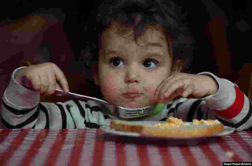 A kétéves Varvara reggelizik egy lengyelországi szállodában, ahol ideiglenesen elszállásolták a zaporizzsjai gyermekotthon lakóit