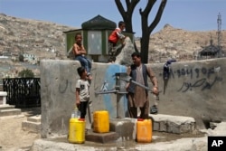 A man and his children collect water from a public water pump in Kabul. (file photo)