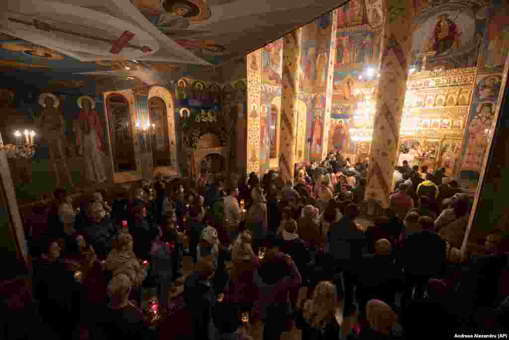 Православни верници со свеќи за време на Велигденската служба во Парохиската црква Бранкуси во Букурешт на 24 април. Присуствуваа и десетици украински бегалци кои живеат во социјален центар што ѝ припаѓа на Црквата.