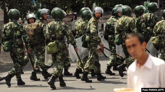 Chinese riot police patrol a street in Urumqi in China's Xinjiang Province. A new study finds that China is hunting Uyghurs and other Muslim minorities through a global dragnet that is increasingly relying on cooperation with governments in the Middle East and South and Central Asia. (file photo)