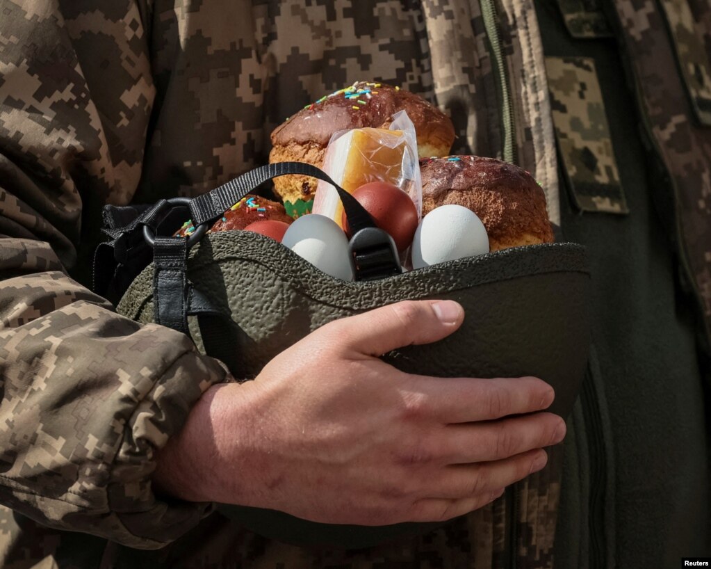 Një ushtar ukrainas mban ëmbëlsirë dhe ushqime tjera në helmetën e tij gjatë shënimit të Pashkëve Ortodokse në Kiev.