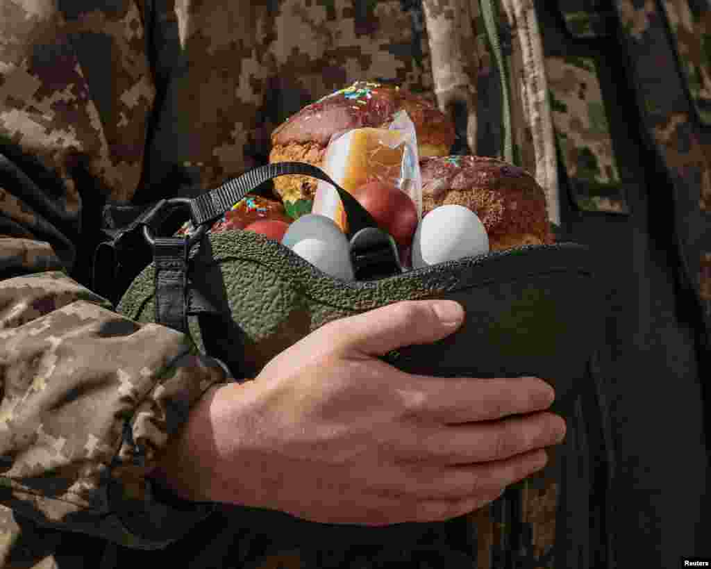 Një ushtar ukrainas mban ëmbëlsirë dhe ushqime tjera në helmetën e tij gjatë shënimit të Pashkëve Ortodokse në Kiev. &nbsp;