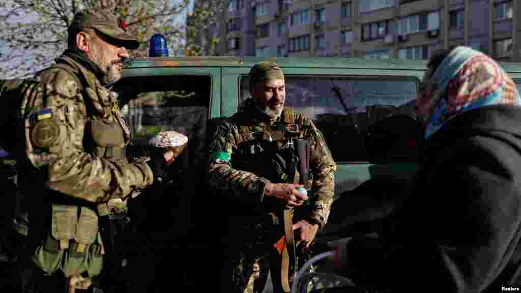 A woman offers consecrated Easter cake and eggs to Territorial Defense members outside St. Andrew&#39;s church and Pyervozvannoho All Saints in Bucha, outside Kyiv.