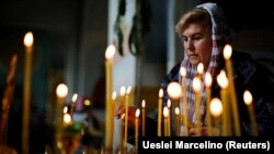 Украинка пали свеќа за време на велигденската богослужба, 24 април, 2022 година