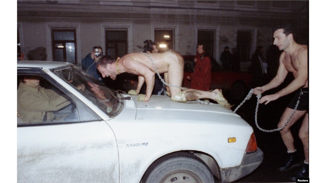Performing as a dog, Oleg Kulik leaps onto a car in the center of Moscow in 1994.