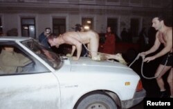 Performing as a dog, Oleg Kulik leaps onto a car in the center of Moscow in 1994.