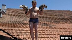 A man rescues cats from a roof during heavy floods in Vojskova, Bosnia-Herzegovina, on May 19.