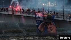 Pristalice osuđenog ratnog zločinca Ratka Mladića drže njegove fotografije i pale baklje na Varadinskom mostu u Novom Sadu, Srbija, 27. avgusta 2026.