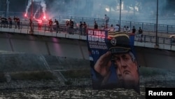 Mbështetës të kriminelit të dënuar të luftës, Ratko Mlladiq, duke mbatur fotografitë e tij dhe duke ndezur flakadanë në urën e Varadinit në Novi Sad, më 27 gusht 2026.