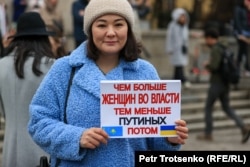 Женщина на митинге с транспарантом с изображением флагов Казахстана и Украины и надписью "Чем больше женщин во власти, тем меньше Путиных потом". Алматы, 8 марта 2022 года