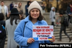 Женщина на митинге с плакатом с изображением флагов Казахстана и Украины и надписью: «Чем больше женщин во власти, тем меньше Путиных потом». Алматы, 8 марта 2022 года