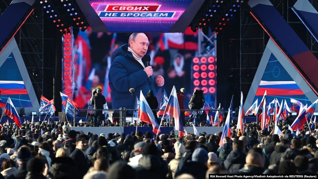 People watch a broadcast of Russian President Vladimir Putin's speech during a concert marking the eighth anniversary of Russia's annexation of Crimea outside Luzhniki Stadium in Moscow on March 18.