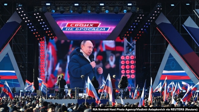 People watch a broadcast of Russian President Vladimir Putin's speech during a concert marking the eighth anniversary of Russia's annexation of Crimea outside Luzhniki Stadium in Moscow on March 18.