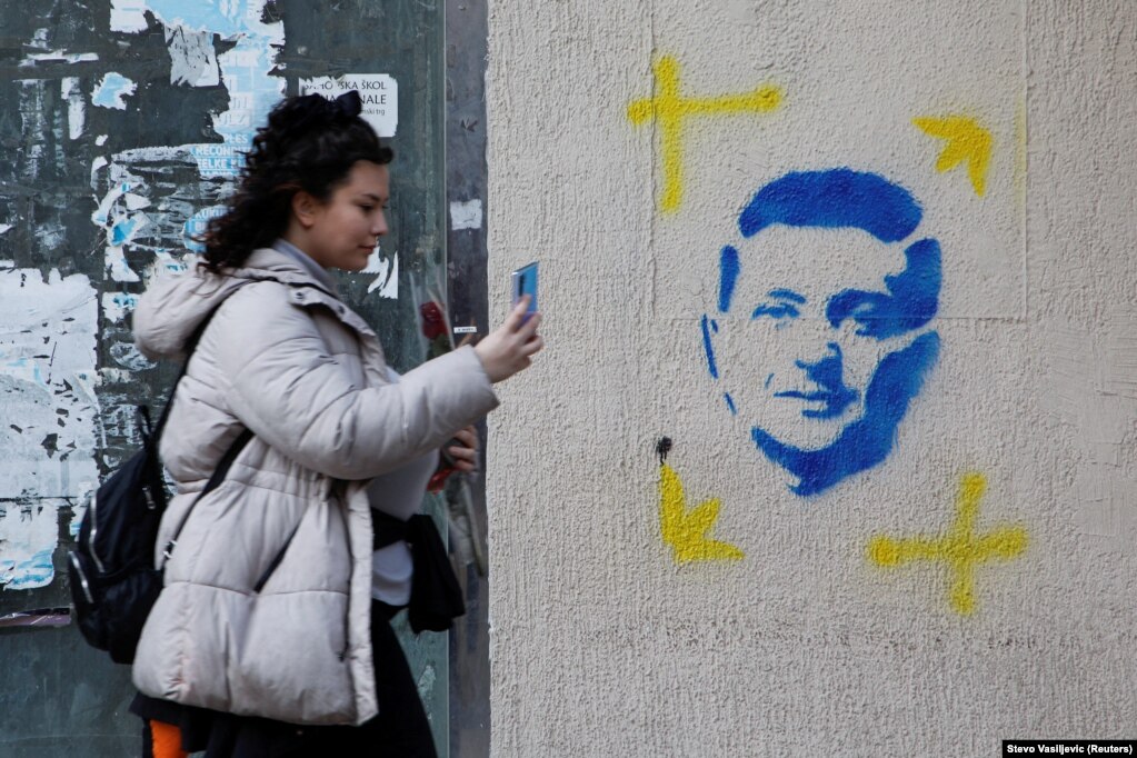 Një grua duke përdorur një telefon mobil para një portreti të vizatuar të presidentit ukrainas, Volodymyr Zelensky, në Podgoricë, Mal i Zi, më 8 mars.