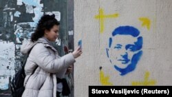 Një vajzë fotografon një grafit me portretin e presidentit të Ukrainës, Volodymyr Zelensky, në Podgoricë.
