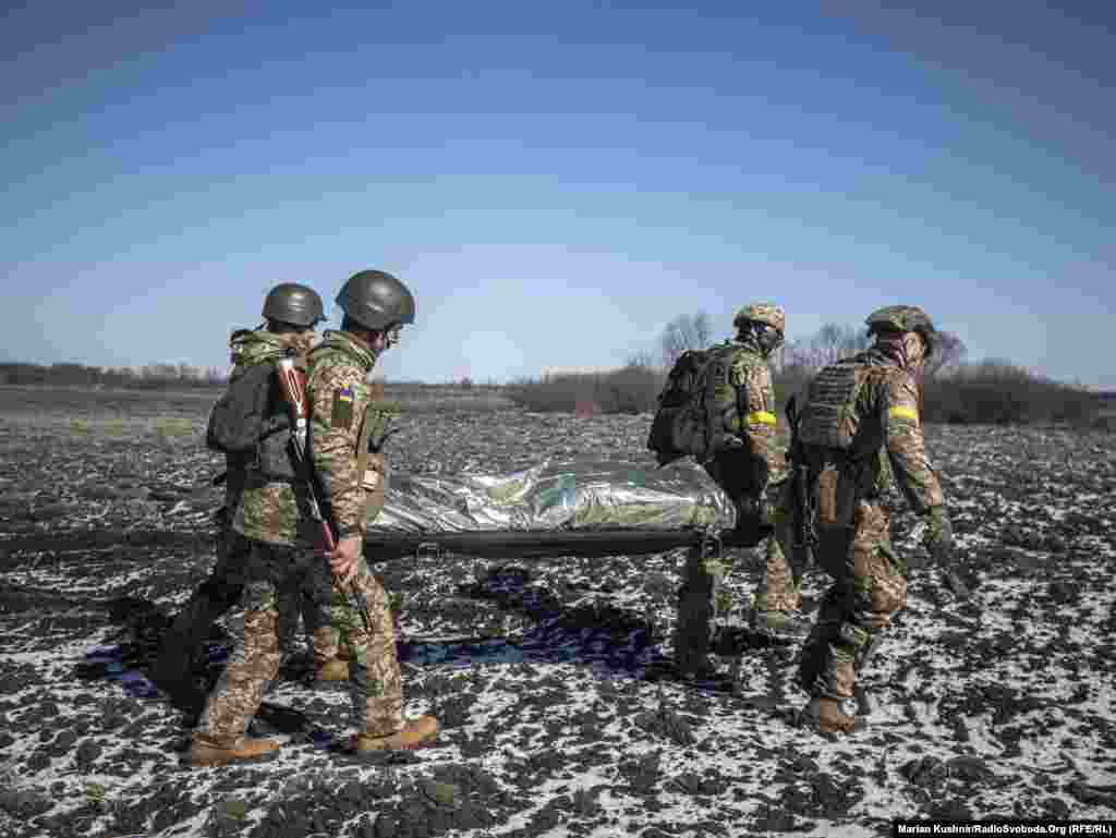 Військові ЗСУ несуть побратима після штурму населеного пункту, де перебували російські військові. Київщина, 10 березня 2022 року