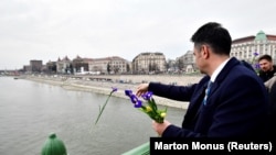 Márki-Zay Péter a háborúban álló ukrán nép előtt tisztelgő, az ukrán zászló színeit idéző virágokat dob a Dunába a március 15-i nagygyűlés előtt