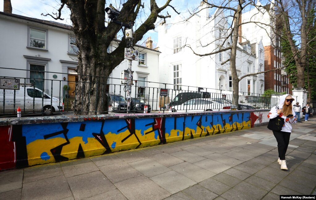 Një grua duke ecur pranë një grafiti në mbështetje të Ukrainës, para Abbey Road Studios, në Londër, Britani, më 14 mars.