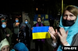 Iranian and Ukrainian nationals hold Ukrainian national flags as they gather in front of the Ukrainian Embassy in Tehran on February 26.