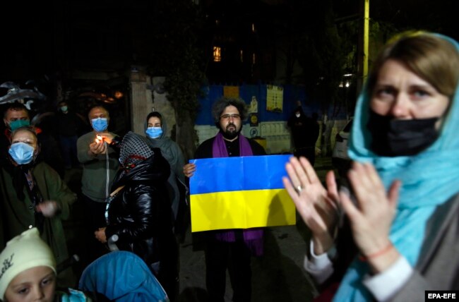 Iranian and Ukrainian nationals hold Ukrainian national flags as they gather in front of the Ukrainian Embassy in Tehran on February 26.