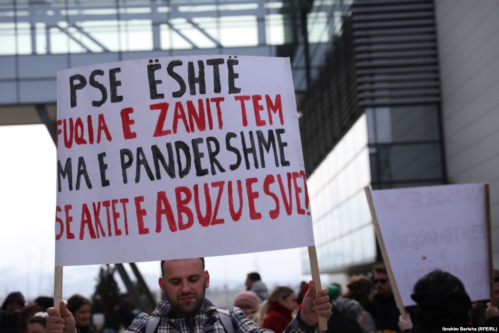 Një pjesëmarrës në protestën e organizuar në Prishtinë më 8 mars, duke mbajtur një pano ku shkruan “Pse është fuqia e zanit tem ma e pandershme se aktet e abuzuesve?”.