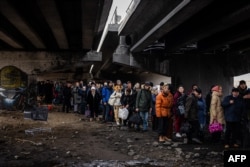 Ucraineni care au fugit din cauza atacurilor rusești din Irpin stau sub un pod distrus. Nord-vest de Kiev, pe 7 martie 2022. Peste 6 milioane de oameni au fugit din Ucraina de când Rusia și-a început invazia pe scară largă.