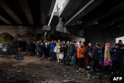 Evacuees stand under a destroyed bridge as they flee the city of Irpin, northwest of Kyiv, on March 7, 2022. More than 6 million people have now fled Ukraine since Russia began its full-scale invasion.