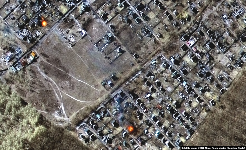Următoarele trei imagini arată case distruse, cratere de impact și incendii în orașul Mosciun, la nord-vest de Kiev.
