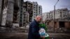 Човек носи тоалетна за домашни любимци на фона на засегната от обстрел жилищна сграда в Чернигов. Снимката е илюстративна