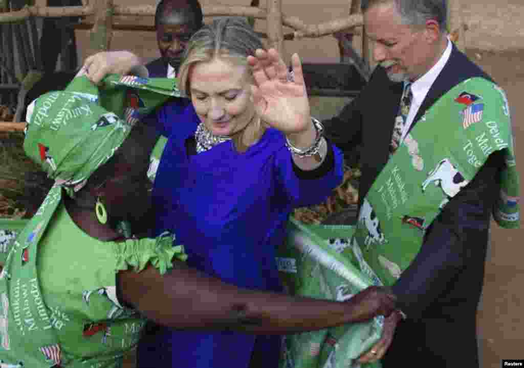 5 августа 2012 года. Глава группы молочных фермеров Малави Эмми Фири закутывает Хиллари Клинтон в национальный костюм. Клинтон была первым Госсекретарем США, посетившим это африканское государство. 