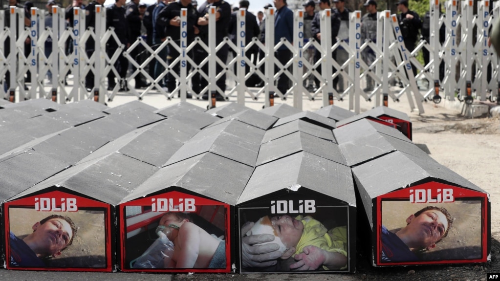 People gather next to symbolic coffins with pictures of Syrian victims and inscriptions that translate as "killer Assad" and "killer Putin" during a protest against Russia for its alleged role in a chemical attack in the Syrian province of Idlib on April 7.