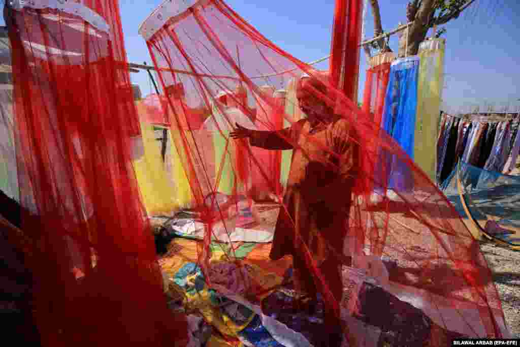 A man waits for customers as he sells anti-mosquito nets beside a road in Peshawar, Pakistan.&nbsp;
