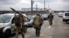 Militari ucraineni cu aruncătoare de grenade și arme cu lunetă, mergând înspre orașul Irpin, la nord-vest de Kiev, scenă a unor bătălii crâncene cu forțele rusești, 13 martie 2022.