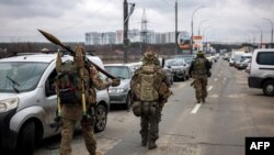 Militari ucraineni cu aruncătoare de grenade și arme cu lunetă, mergând înspre orașul Irpin, la nord-vest de Kiev, scenă a unor bătălii crâncene cu forțele rusești, 13 martie 2022.