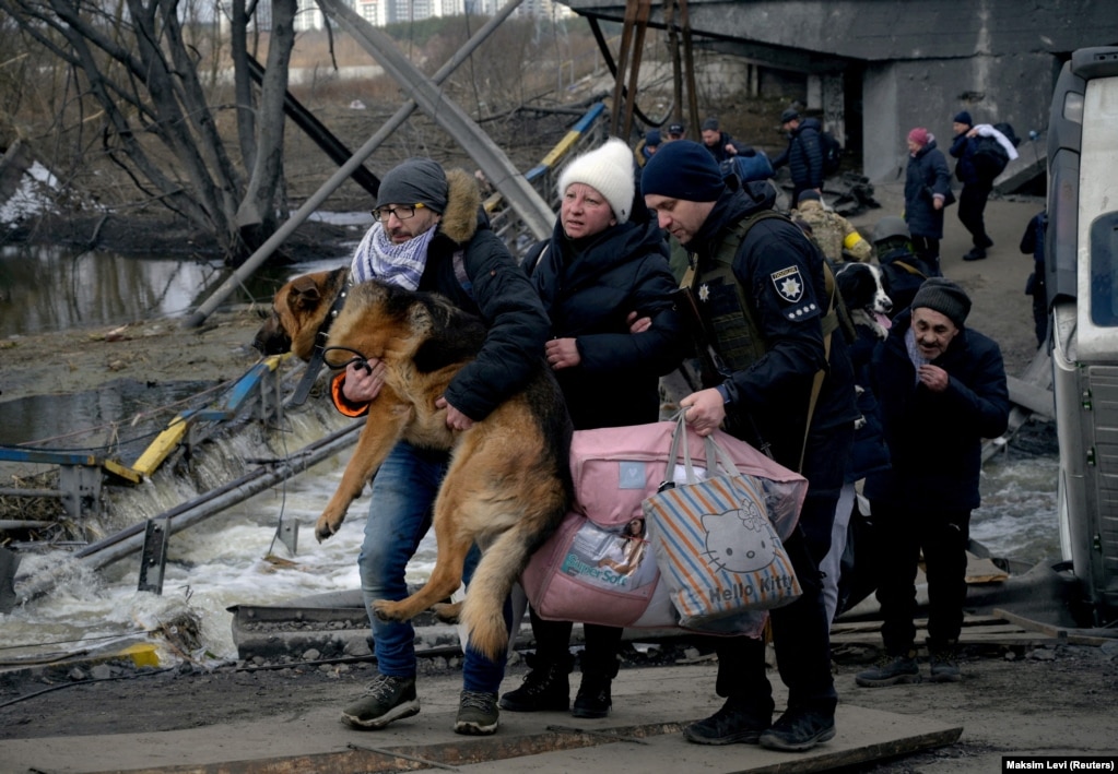 Një burrë duke mbajtur një qen, në Irpin, afër Kievit, teksa njerëzit iknin nga sulmet ruse, më 9 mars 2022.