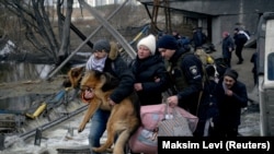 Egy menekülő férfi cipeli a kutyáját a lebombázott irpinyi híd alatt március 9-én