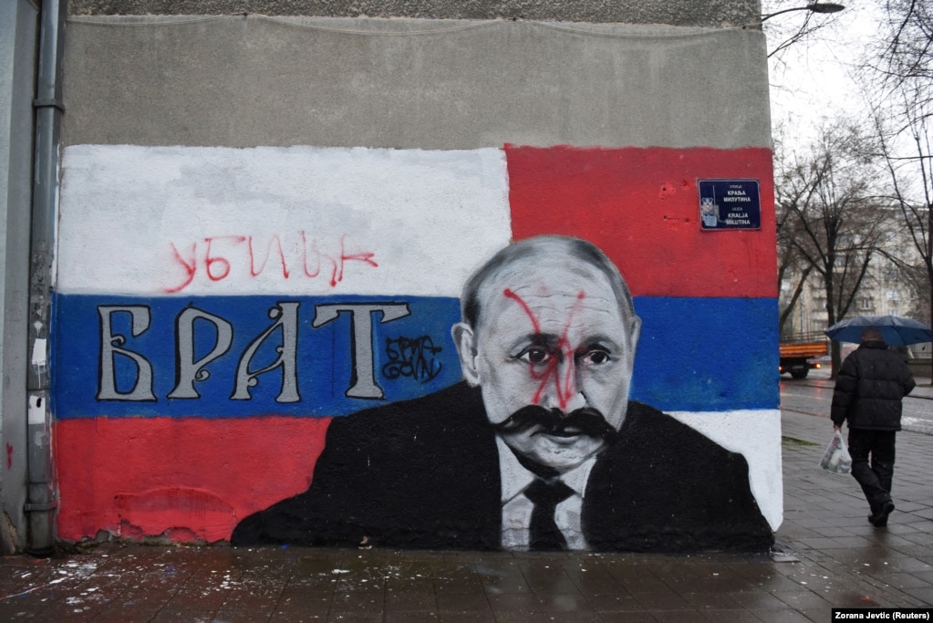 Një burrë duke ecur pranë një murali me portretin e presidentit të Rusisë, Vladimir Putin, i cili është njollosur me ngjyrë të kuqe, dhe me fjalën "Vrasës", mbi mbishkrimin "Vëlla", në Beograd, Serbi, më 6 mars.