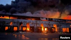 Një depo shihet duke u djegur, si pasojë e bombardimeve në një fshat në rajonin e Kievit. 12 mars 2022.