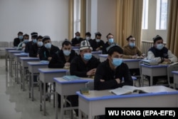 Ethnic Uyghurs sit in a classroom during an organized press tour at an internment facility that Beijing has labeled a "vocational training center."