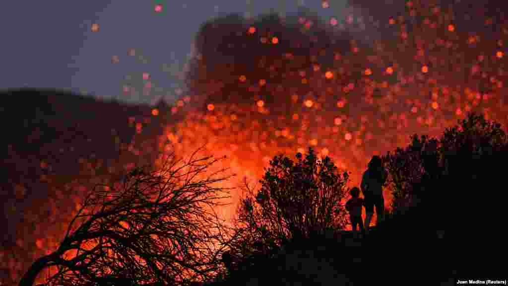 Egy nő sétál fel gyermekével, hogy közelebbről láthassa a La Palma szigetén kitört​ vulkánt&nbsp;