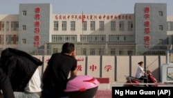 Огороженная территория средней школы в Кашгаре, надпись на здании гласит: «Усердно учись, чтобы осуществить китайскую мечту» 